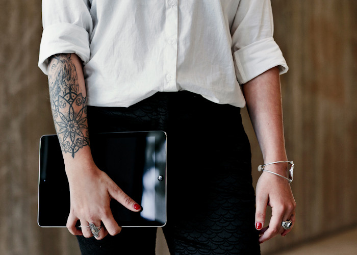 person med tatoveringer som holder en tablet